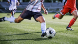 soccer player with meniscus tear dribbling on the soccer pitch