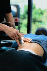 a therapist of sportential doing laser treatment to a back pain patient